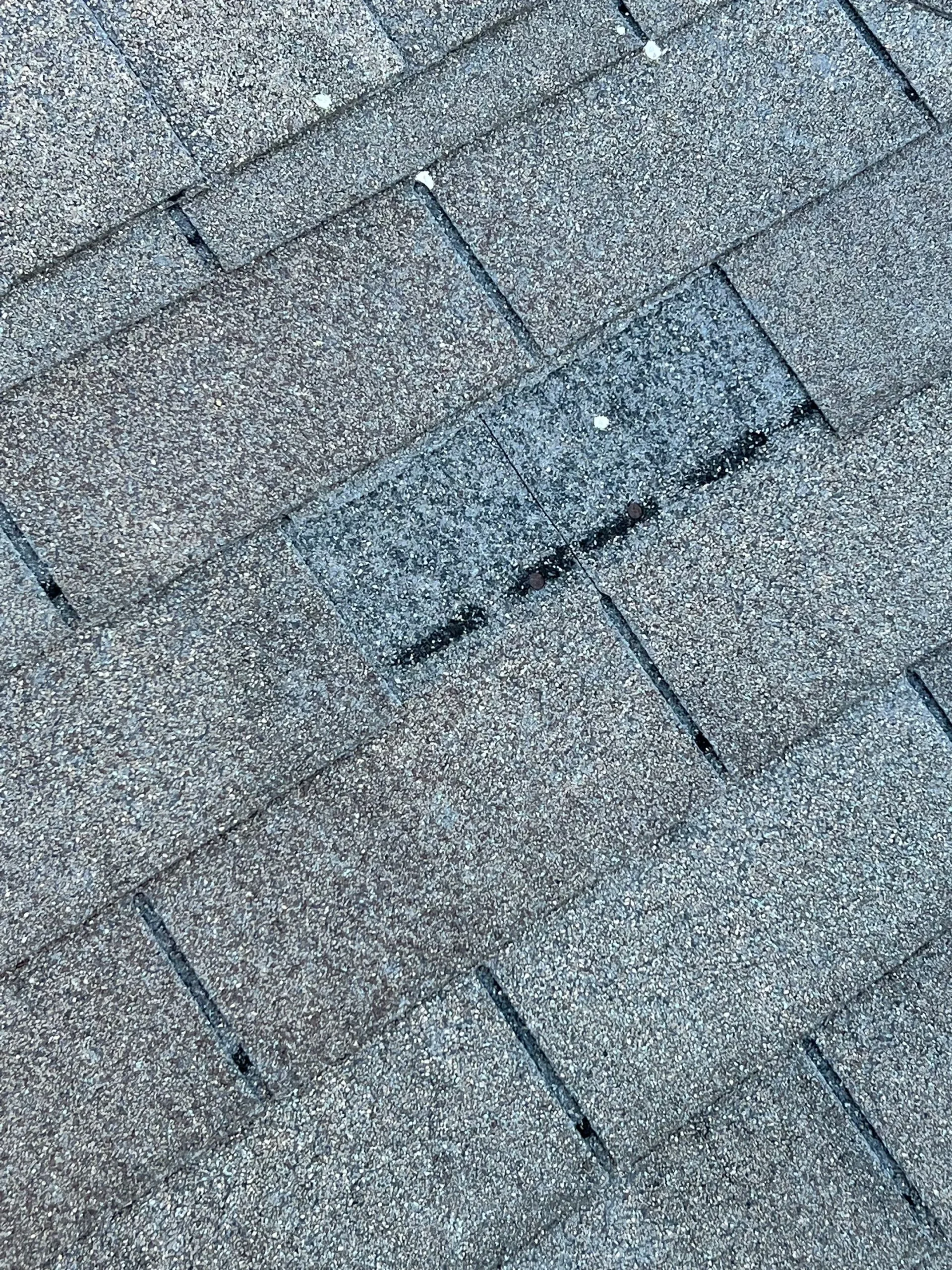 Roof section with missing shingles exposing underlayment