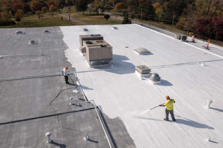 Aerial view of workers applying reflective roof coating on a flat commercial roof in Texas