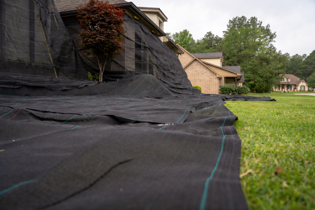 black catch-all netting system protecting house and lawn during roofing project with no debris