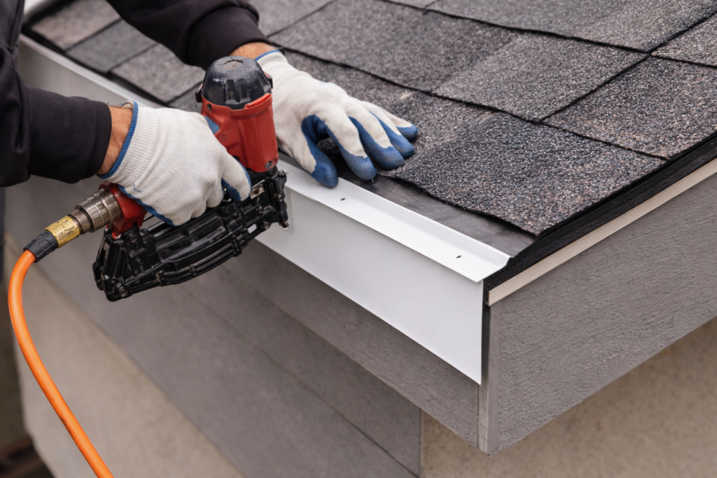 Roofing contractor installing metal drip edge along roof edge during roof replacement