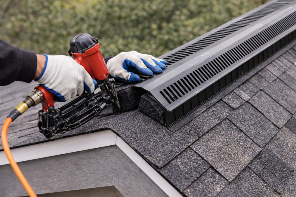 Roofing contractor installing ridge vent on shingle roof during roof replacement
