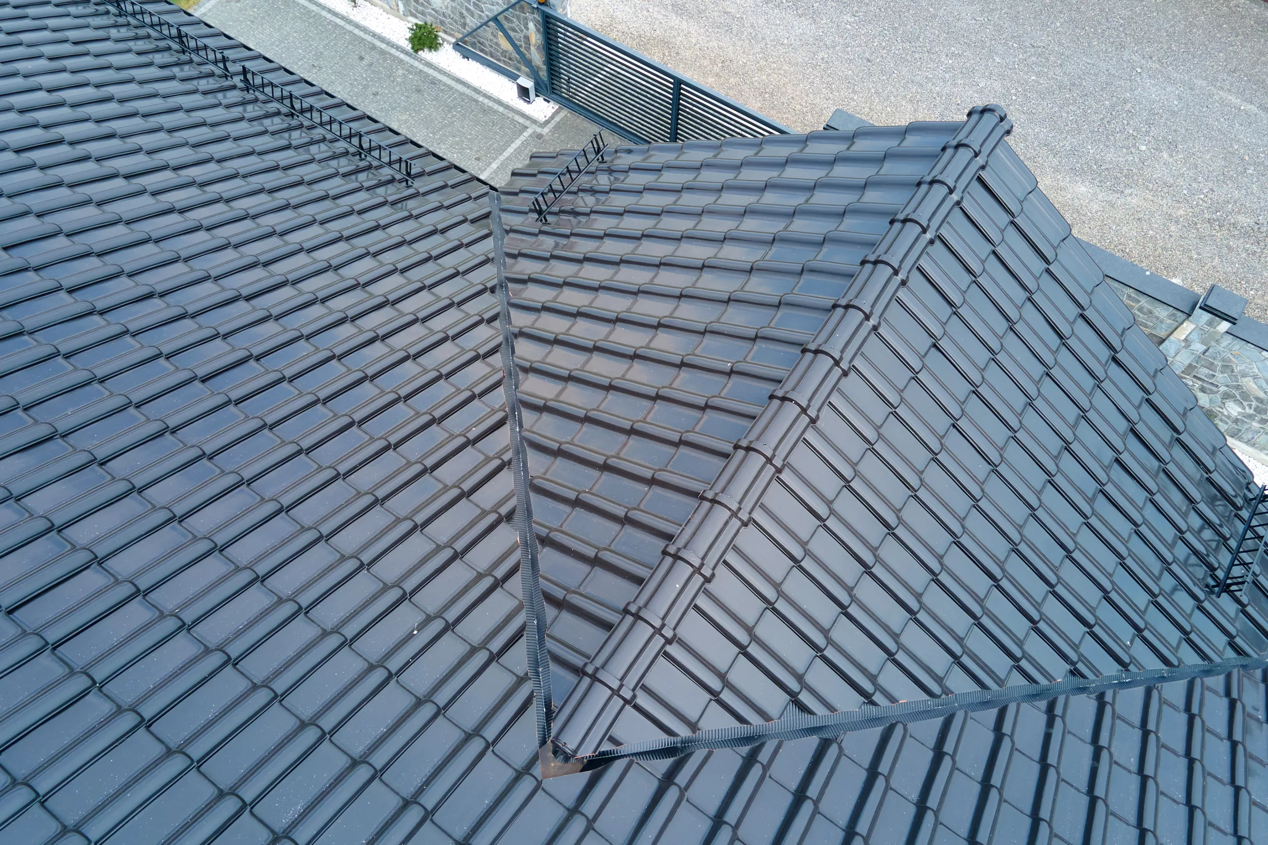 The image is of the view from above the house toward the cement on the ground. There is new black roofing