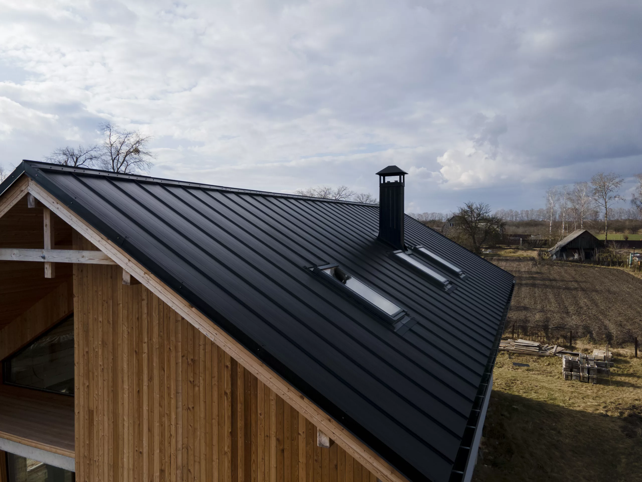 There is a home in the country  with a black metal roof