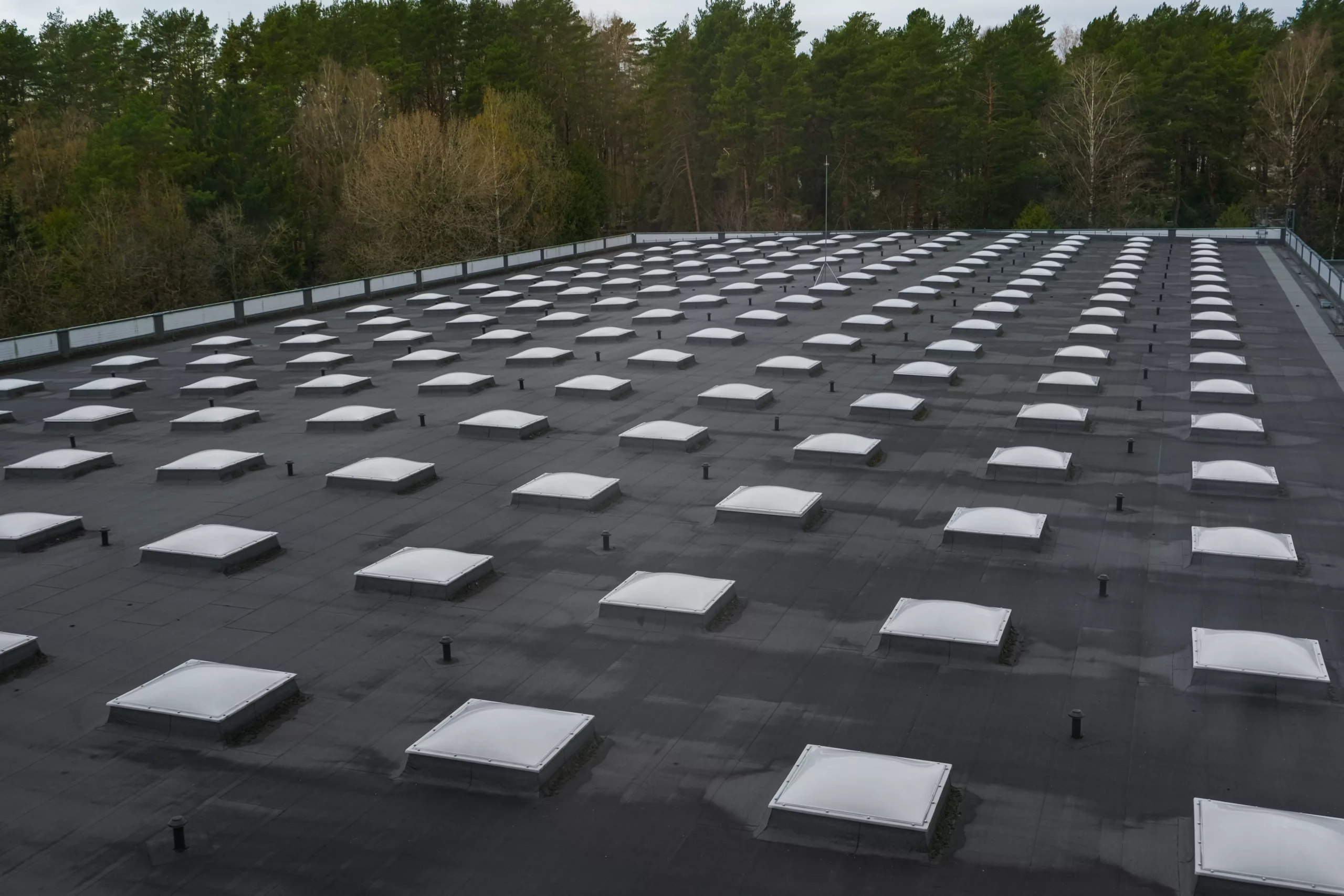 A flat, black roof has many vents and skylights