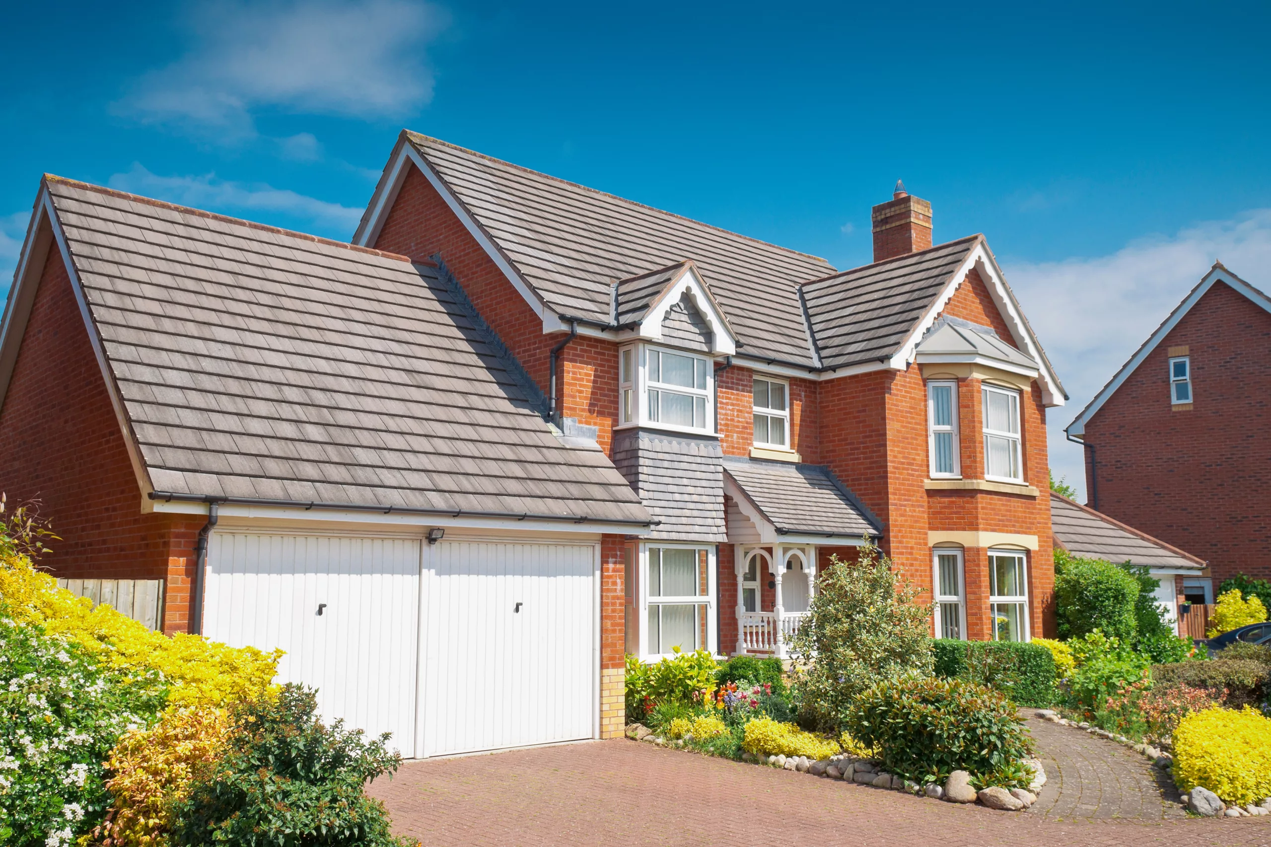 Shingle roof on brick house with windows and white garage