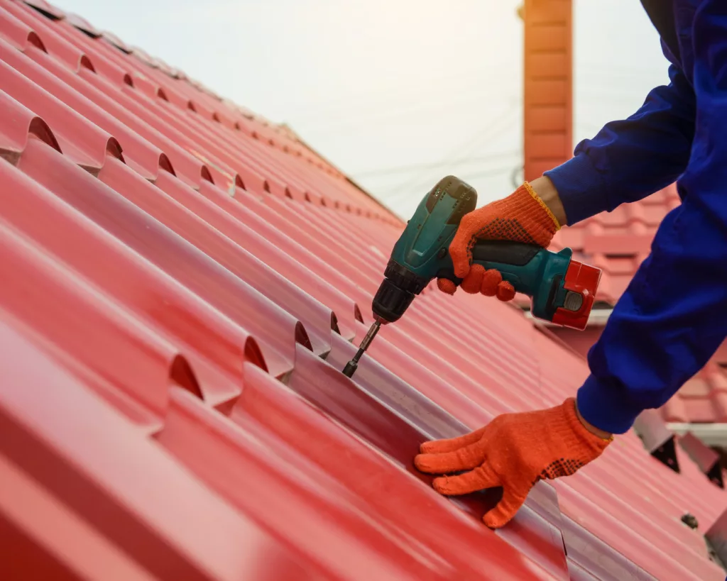 Roofer repairing red metal residential roof