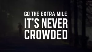 Graphic of the words, “Go The Extra Mile, It’s Never Crowded” against a deeply silhouetted image of a woman running down a wooded road