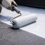Close-up of roller applying membrane on commercial flat roof surface