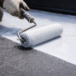 Close-up of roller applying membrane on commercial flat roof surface