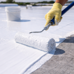 Close up of contractor applying polyurethane roof coating with roller on flat commercial roof