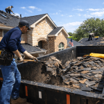 Roof material removal and disposal in Texas with roofing crew safely removing old shingles and loading debris into a dumpster