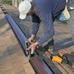 Technician performing roof vent repair on asphalt shingle ridge vent