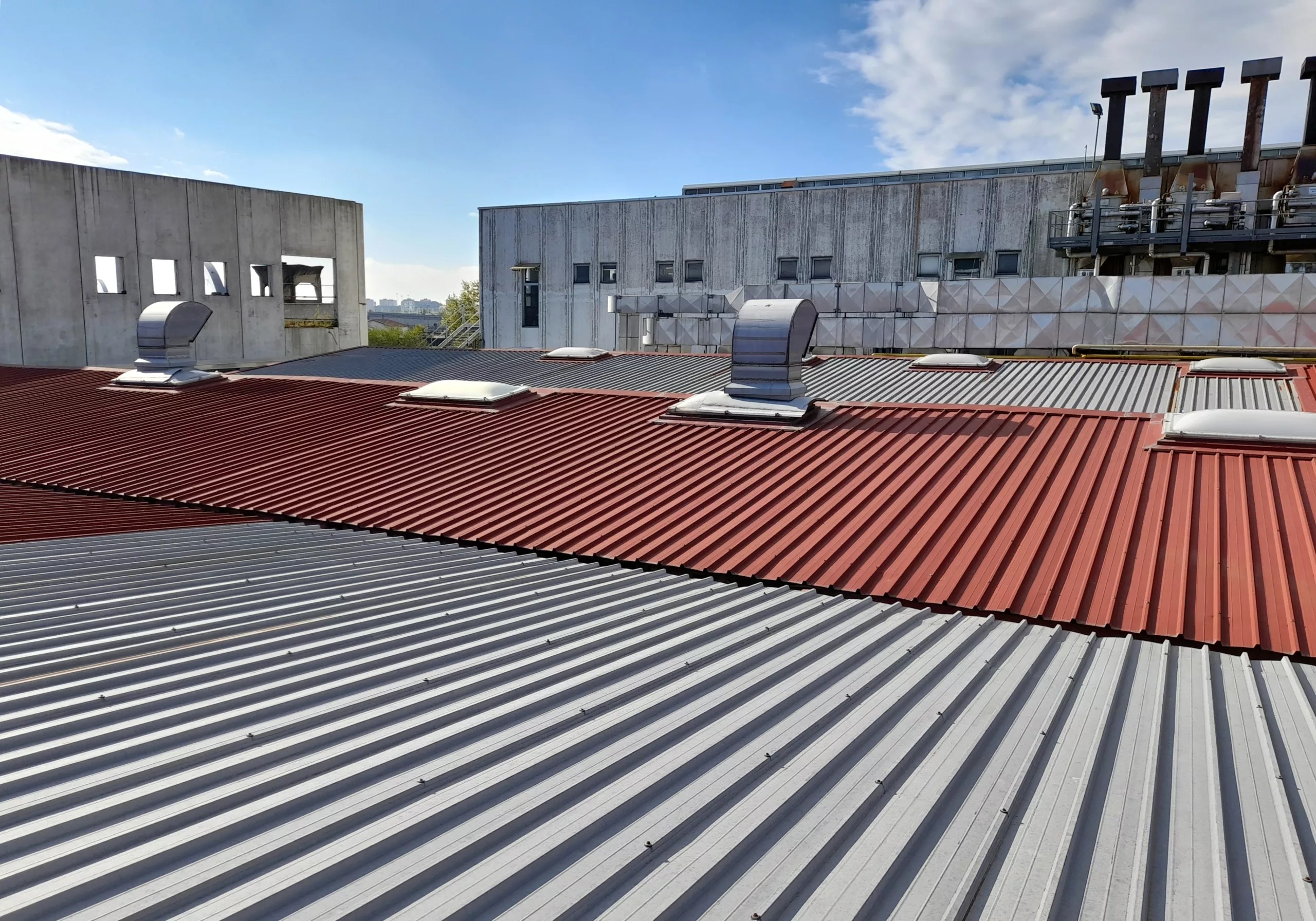 A commercial building has red and grey metal roofing