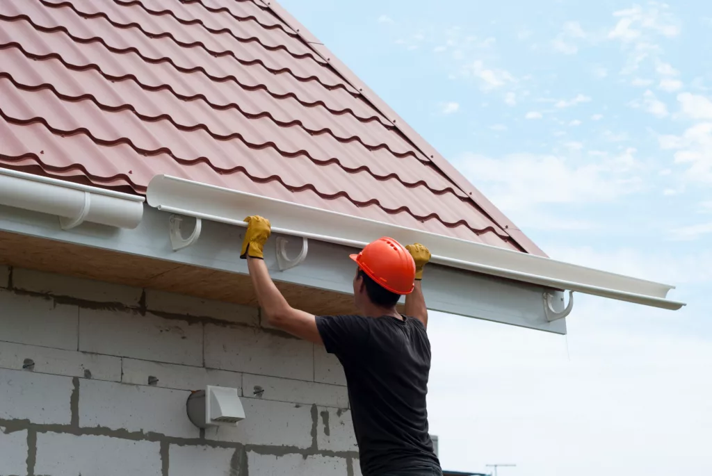 Worker installing new gutters on a home