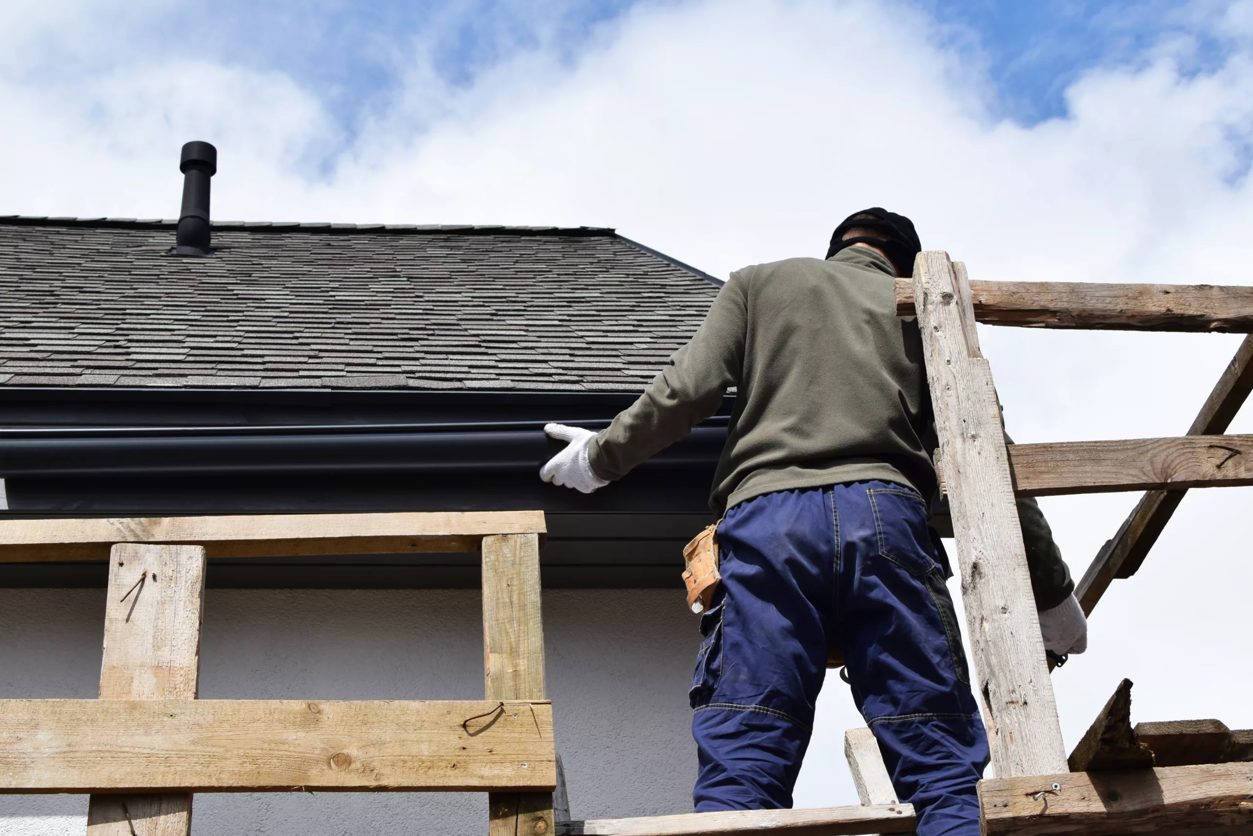 Worker installer gutters on a house