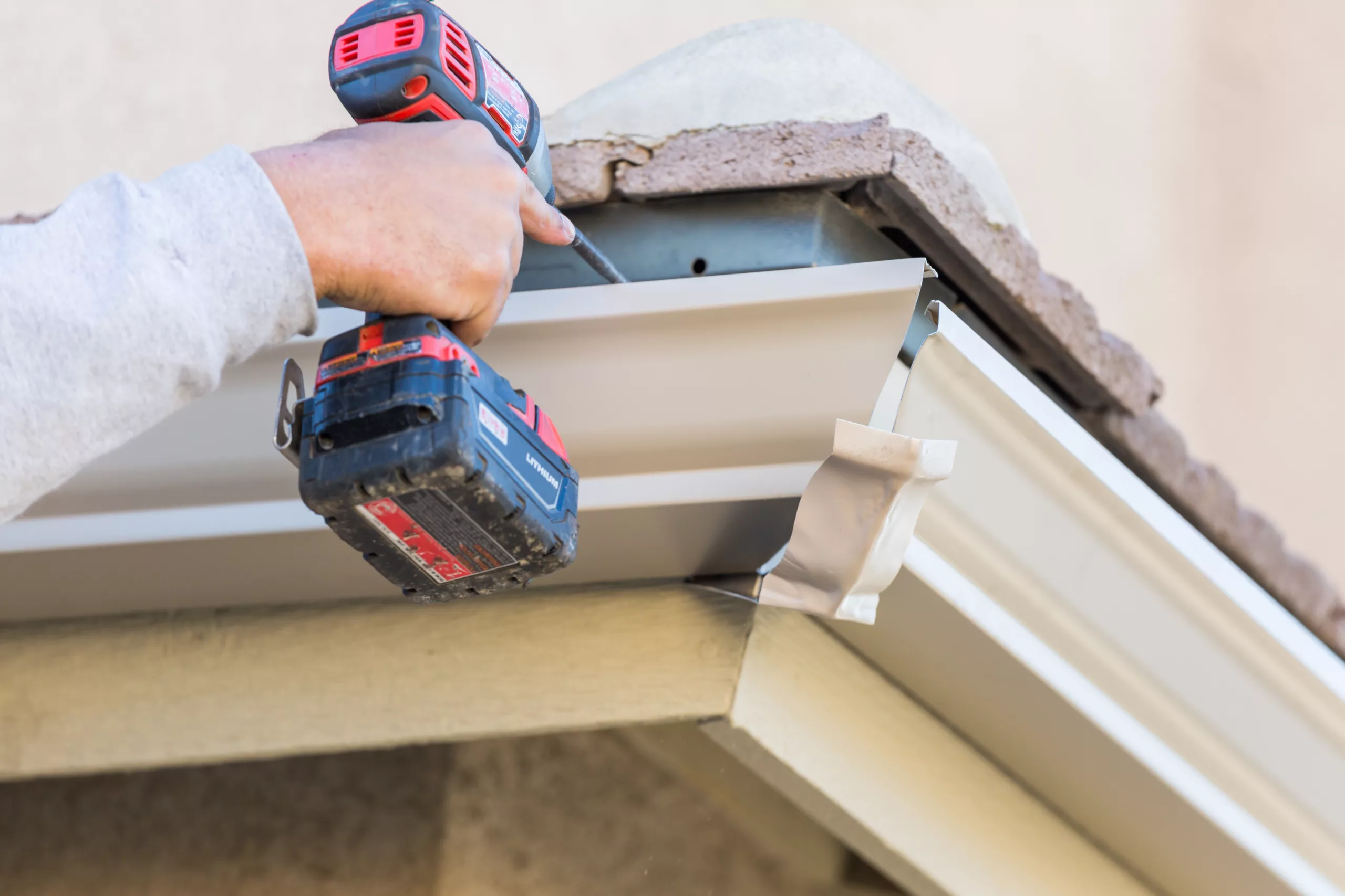 Roofer installing gutters on a house