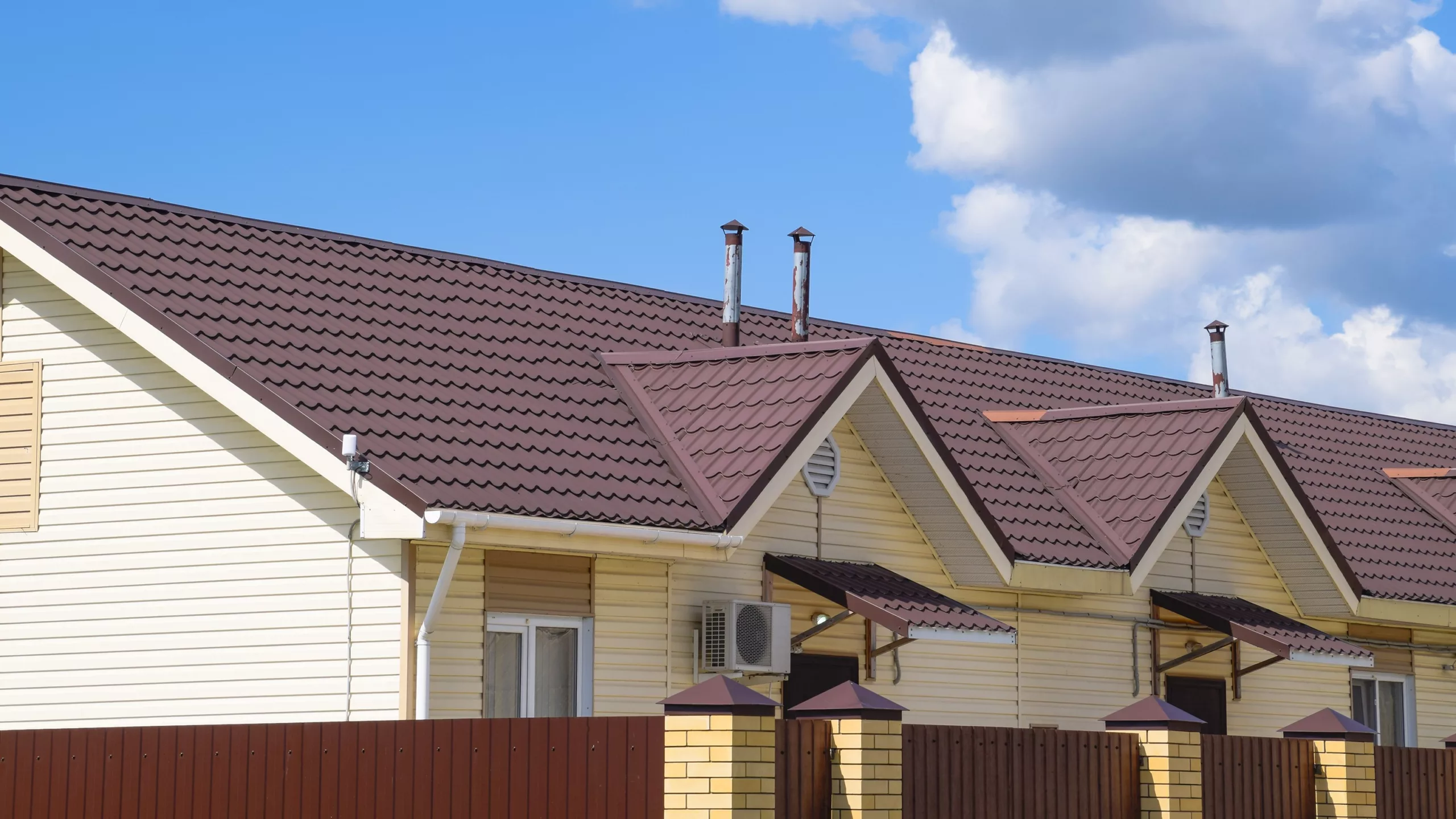 Large wide home with off-white siding and red metal tile roofing