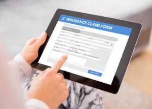Person filling out insurance claim form on a tablet