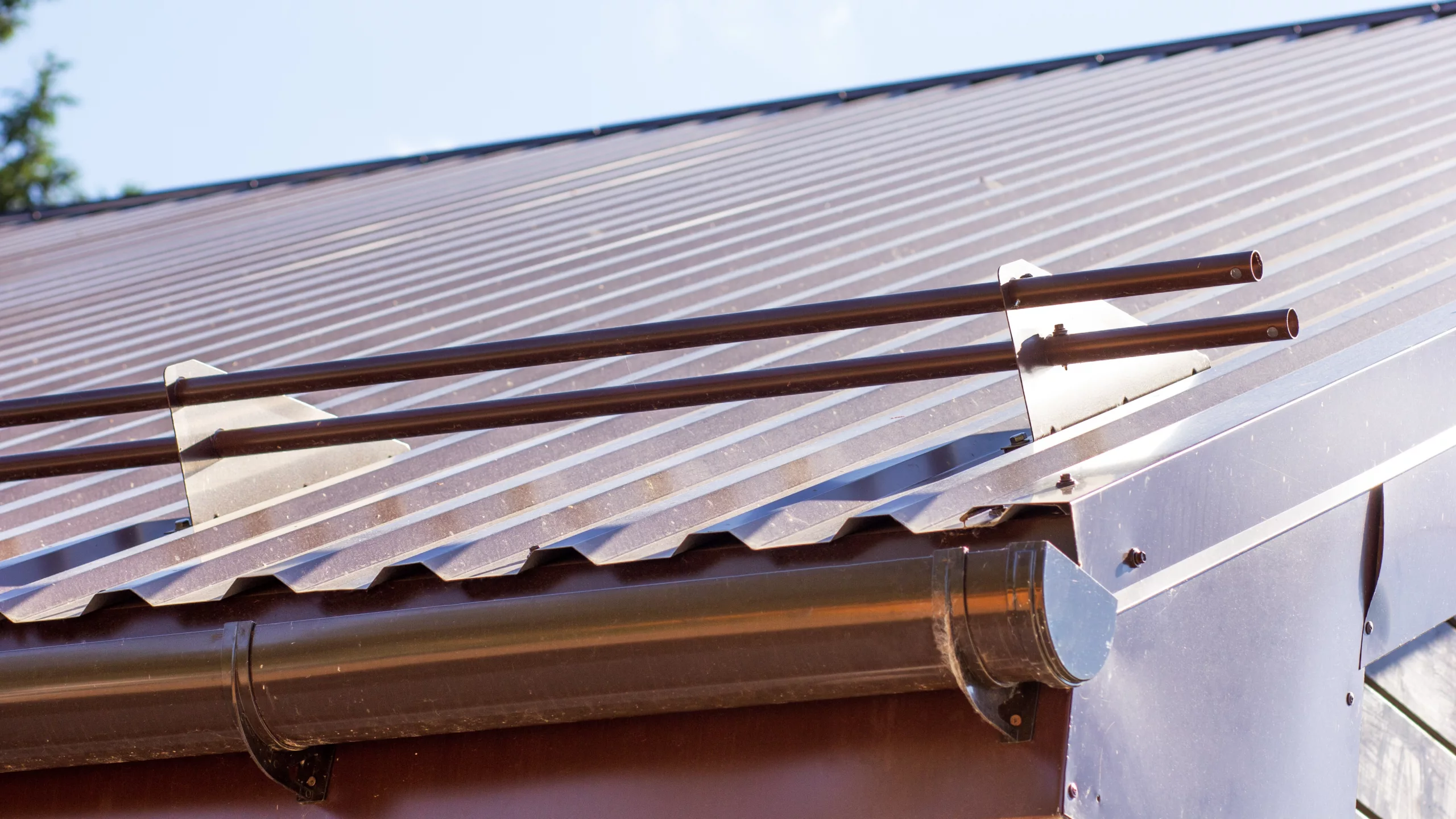 Red metal roof on home with aluminum gutter system