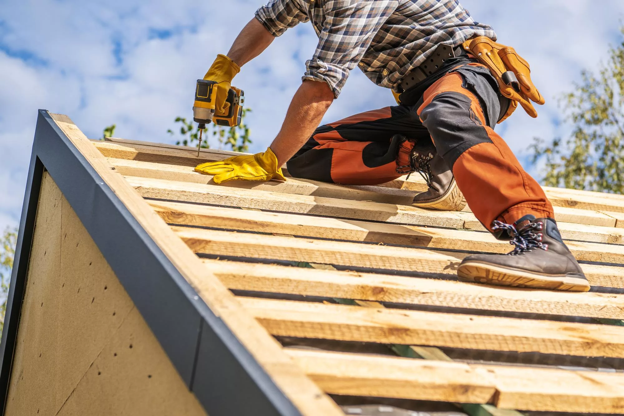 A roofing contractor is on a roof installing trusses and preparing the roof for roofing materials