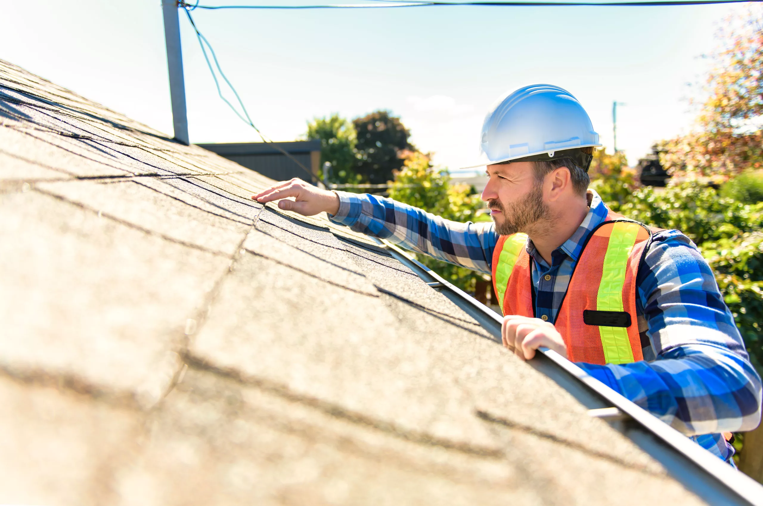 Roof inspector with hard hat looking at shingles