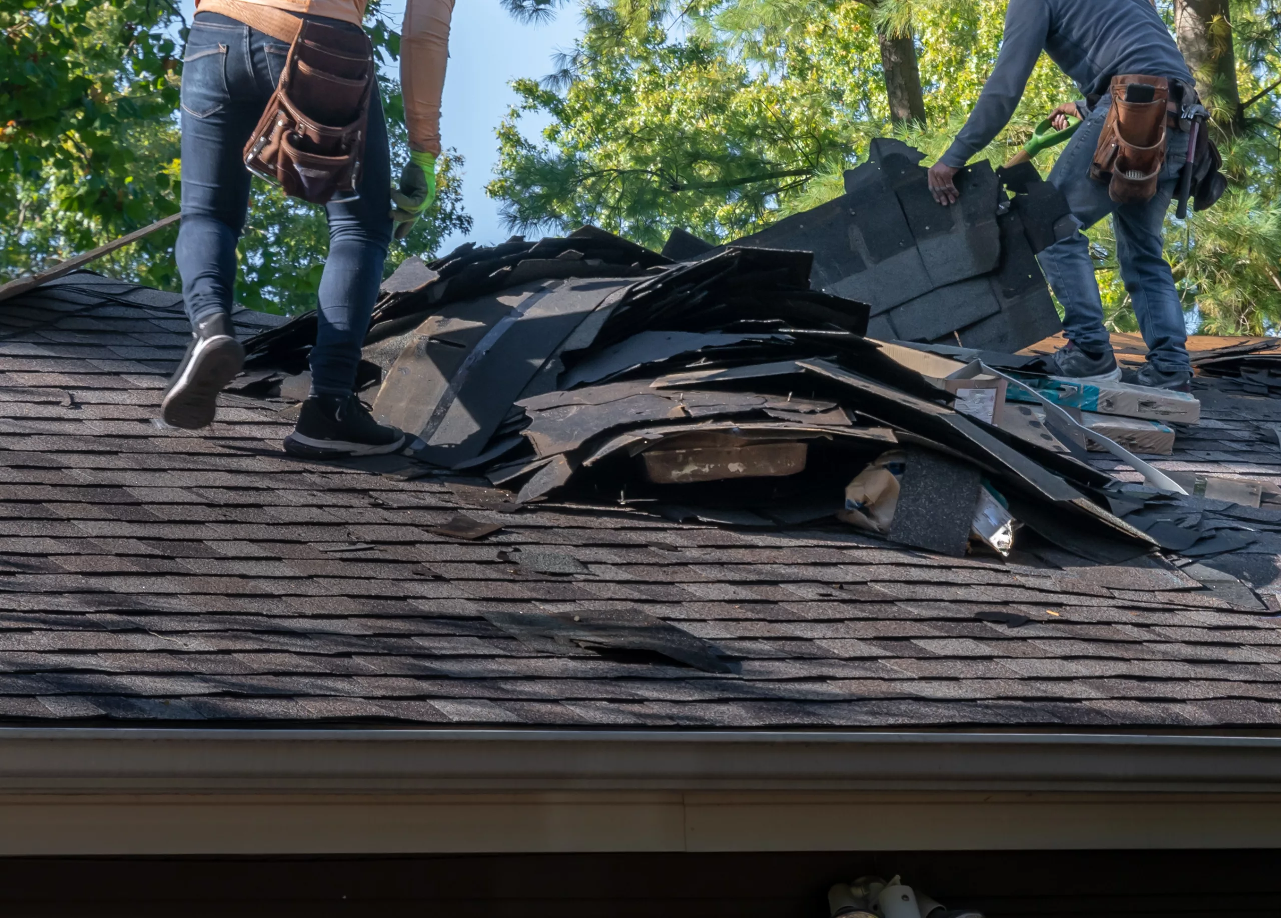 Workers repairing a residential roof after a storm damage