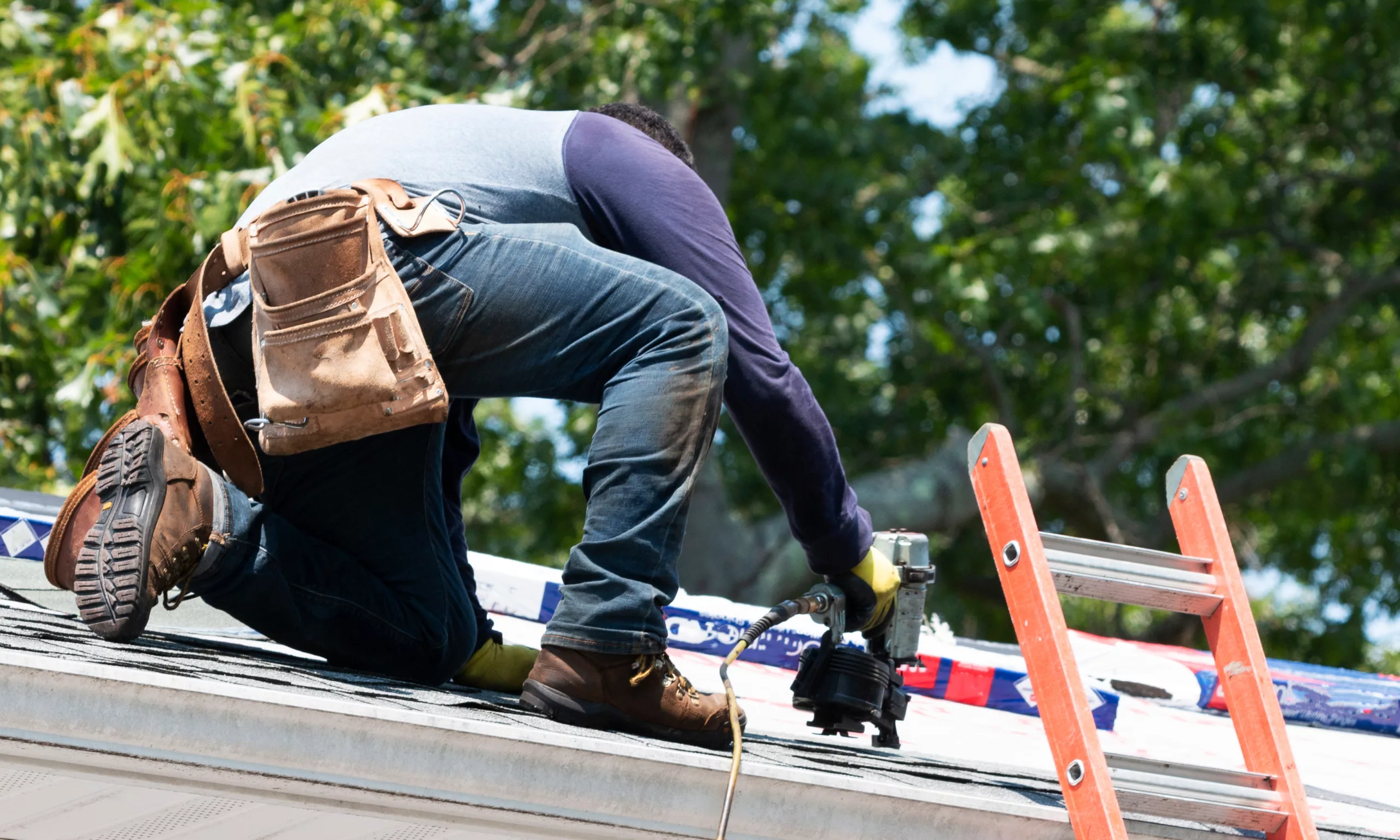 Roofer repairing a residential roof with a nail gun