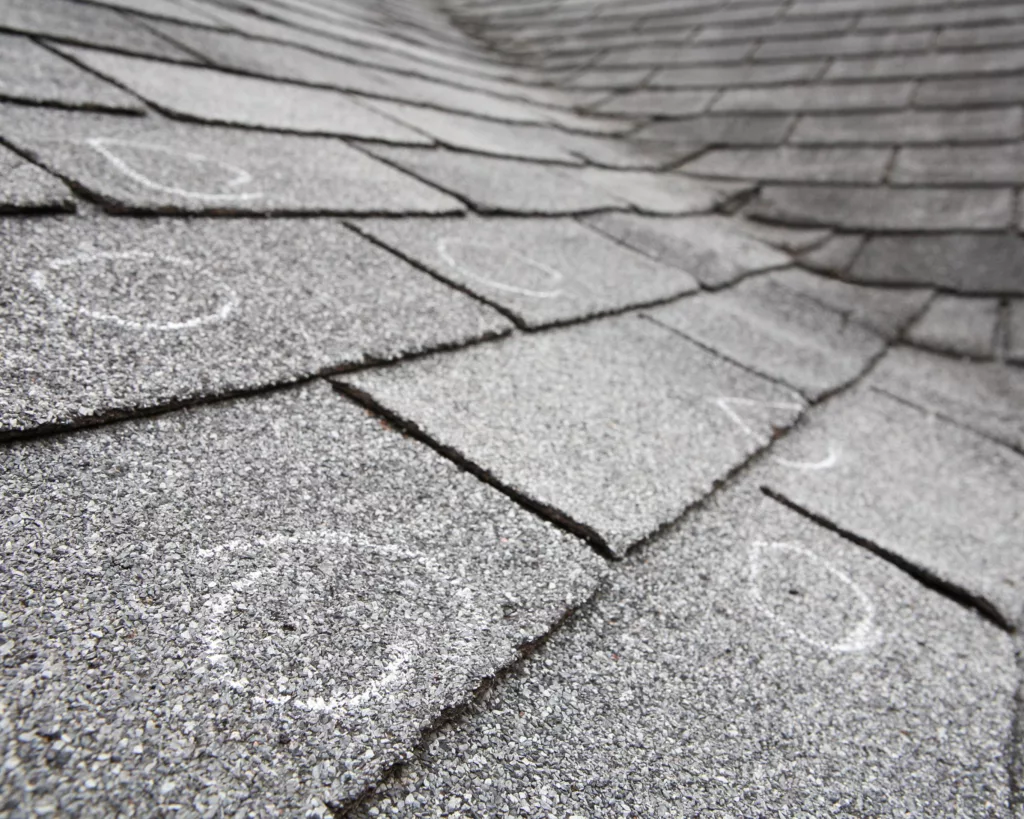 Hail damage marked on gray asphalt shingle roof