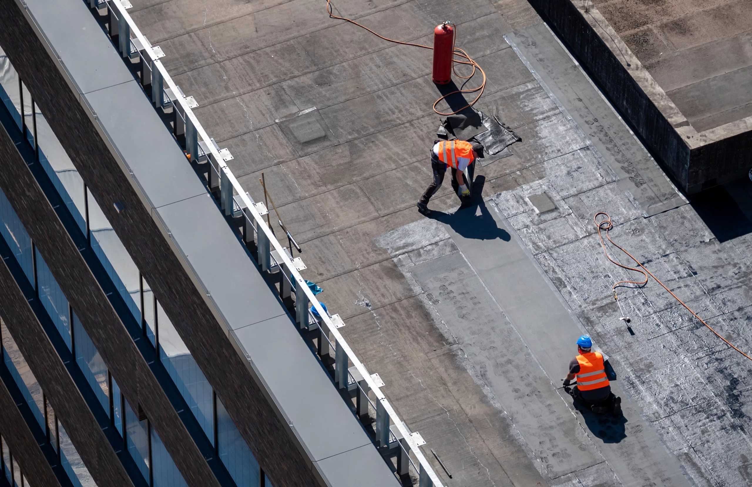 Two workers repairing a flat roof
