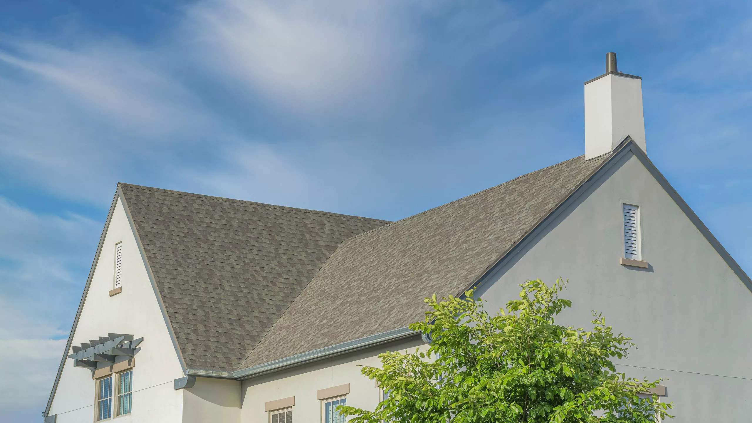 View of new asphalt shingle roof on large building with a beautiful sky view